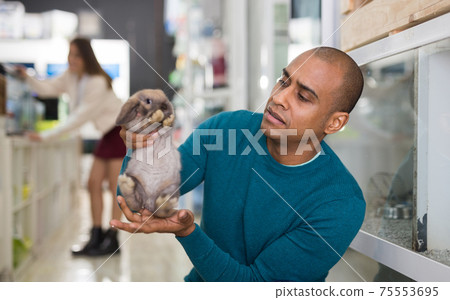 Man holding cute rabbit in pet shop Man holding cute rabbit in pet shop 75553695