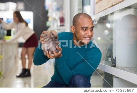 Man holding cute rabbit in pet shop Man holding cute rabbit in pet shop 75553697