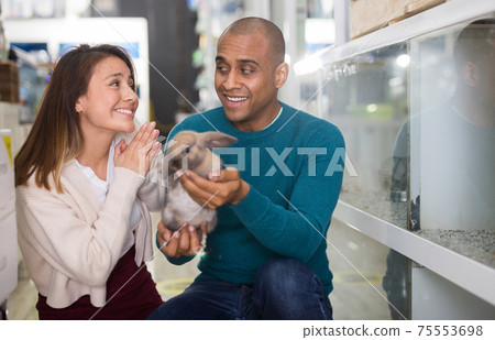 Happy couple holding rabbit in pet sho Happy couple holding rabbit in pet sho 75553698