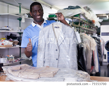 Worker of laundry showing clean clothing 75553700