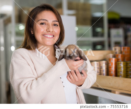 Happy woman holding rabbit in pet shop 75553716