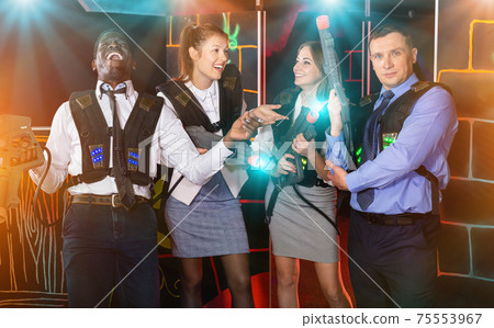 Group portrait of happy colleagues having fun at laser tag room 75553967