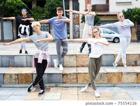 Teen boys and girls dancing modern choreography on city street 75554116