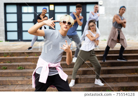 Confident teenager street dancer performing with group 75554128