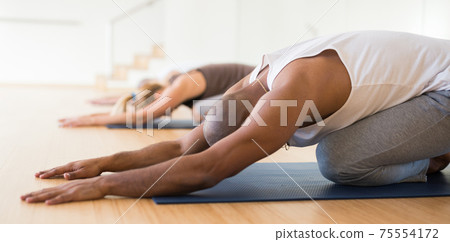 Woman and men stretching during group yoga training 75554172