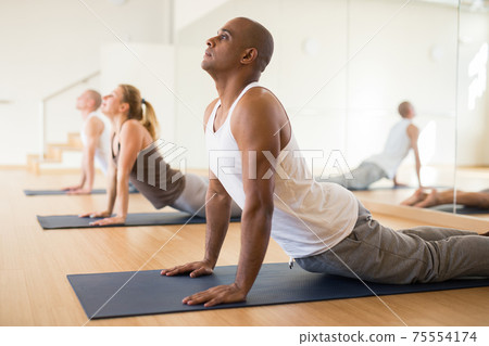 Hispanic man performing stretching asana Urdhva Mukha Shvanasana 75554174