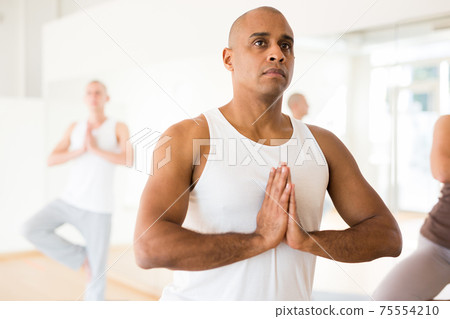 Group yoga classes in modern fitness center 75554210