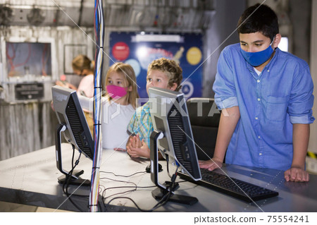 Tweens in protective masks using computer in lost room bunker Tweens in protective masks using computer in lost room bunker 75554241