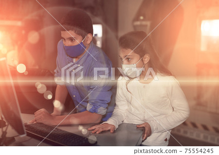Tweens in protective masks using computer in quest room, toned image Tweens in protective masks using computer in quest room, toned image 75554245