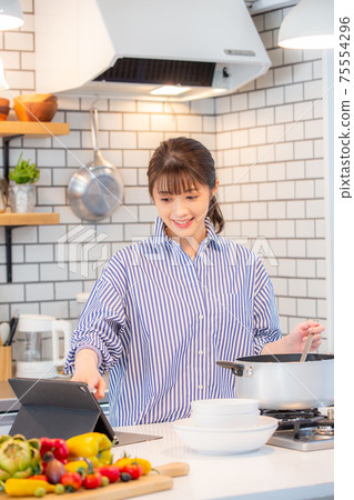 女人看著平板電腦做飯 女人看著平板電腦做飯 75554296
