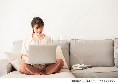 一個女人在沙發上使用電腦 75554359