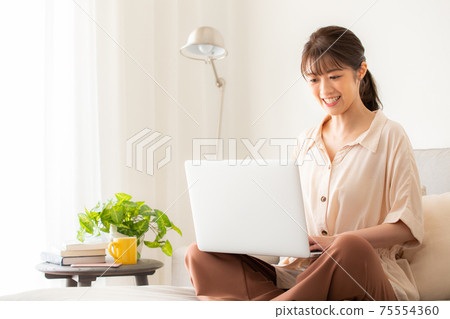 一個女人在沙發上使用電腦 75554360