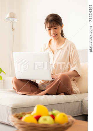 一個女人在沙發上使用電腦 75554361