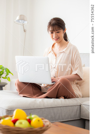 一個女人在沙發上使用電腦 75554362