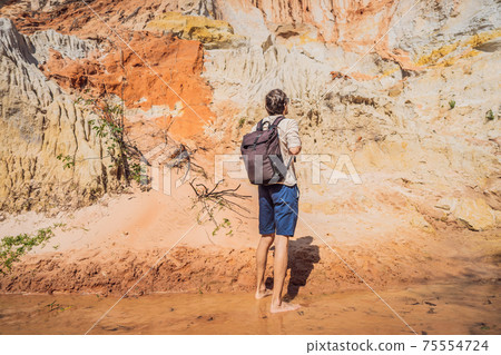 Man tourist on the Fairy stream among the red dunes, Muine, Vietnam. Vietnam opens borders after quarantine COVID 19 Man tourist on the Fairy stream among the red dunes, Muine, Vietnam. Vietnam opens borders after quarantine COVID 19 75554724