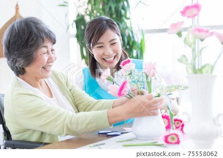 Nursing image: Senior women and caregivers enjoying flower arrangements 75558062