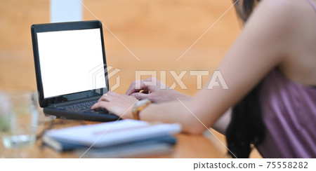 Behind shot of beautiful woman is working with a white blank screen computer laptop at the wooden desk. Behind shot of beautiful woman is working with a white blank screen computer laptop at the wooden desk. 75558282