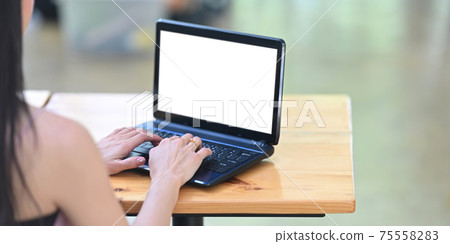 Behind shot of beautiful woman is working with a white blank screen computer laptop at the wooden desk. Behind shot of beautiful woman is working with a white blank screen computer laptop at the wooden desk. 75558283