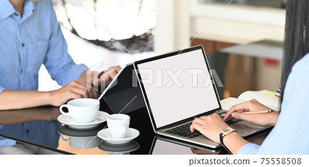 Cropped image of business people working together while sitting together at the modern glass table over comfortable workplace as background. Cropped image of business people working together while sitting together at the modern glass table over comfortable workplace as background. 75558508