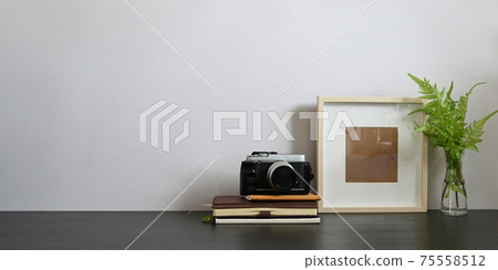 Photo of black working desk along with book, notebook, picture frame, potted plant and camera putting together on it with white cement wall as background. Orderly workspace concept. Photo of black working desk along with book, notebook, picture frame, potted plant and camera putting together on it with white cement wall as background. Orderly workspace concept. 75558512