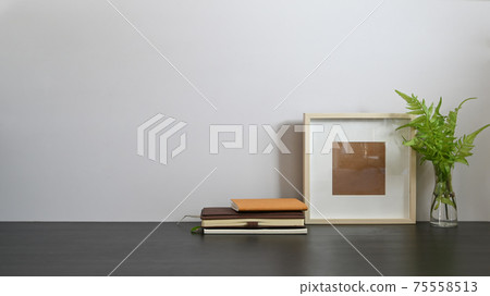 Photo of black working desk along with book, notebook, picture frame, potted plant putting together on it with white cement wall as background. Orderly workspace concept. Photo of black working desk along with book, notebook, picture frame, potted plant putting together on it with white cement wall as background. Orderly workspace concept. 75558513