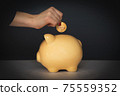 Crop woman putting coin in piggy bank 75559352