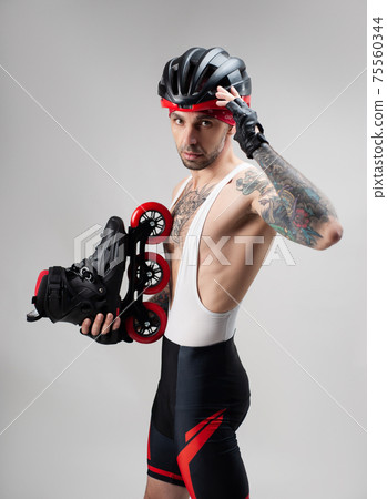 a man in sports clothes and a helmet with roller skates in his hands on a white background 75560344