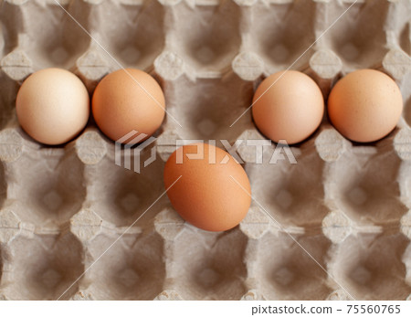 Several brown eggs lie in a row in a large cardboard storage bag Several brown eggs lie in a row in a large cardboard storage bag 75560765