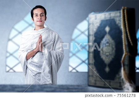 Asian Muslim man in ihram clothes standing with greeting gesture 75561278