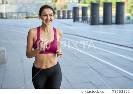 Smiling young female running early in the morning 75563132