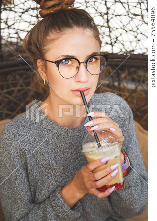 Young millenial hipster woman drinks cocktail in outdoors cafe Young millenial hipster woman drinks cocktail in outdoors cafe 75564096