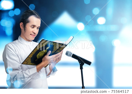 Asian Muslim man standing and reading the Quran 75564517