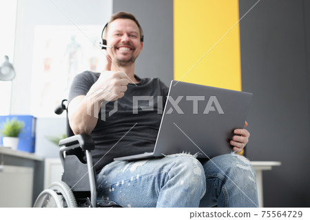 Man in wheelchair with headphones showing thumb up Man in wheelchair with headphones showing thumb up 75564729