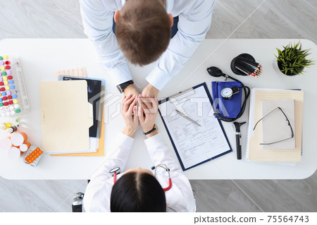 Doctor holding patients hands in clinic top view 75564743