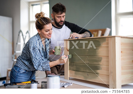 Mid adults couple painting furniture indoors at home, relocation and diy concept. Mid adults couple painting furniture indoors at home, relocation and diy concept. 75564785