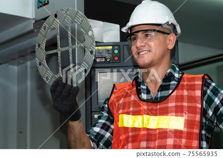Smart factory job worker looking at machine part in manufacturing workshop 75565935