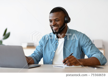 Online Education. Black Guy In Headphones Study With Laptop And Taking Notes Online Education. Black Guy In Headphones Study With Laptop And Taking Notes 75568659