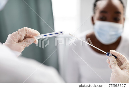 Doctor taking PCR test sample from potentially infected afro woman 75568827