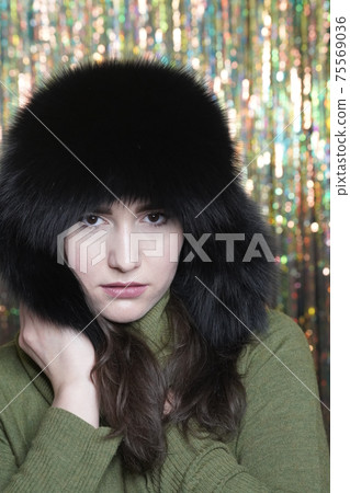 Portrait of casual style woman in winter fur hat close-up, face and hands on glittering background 75569036