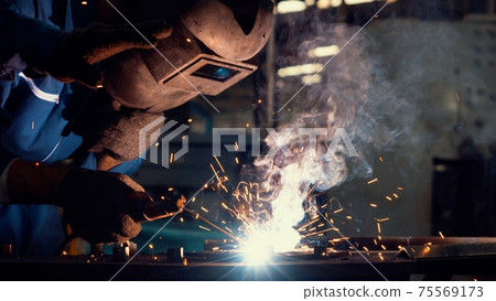 Skillful metal worker working with arc welding machine in factory 75569173