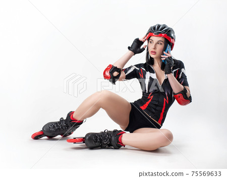 a slender woman in sportswear and a helmet on roller skates on a white background is talking on the phone 75569633