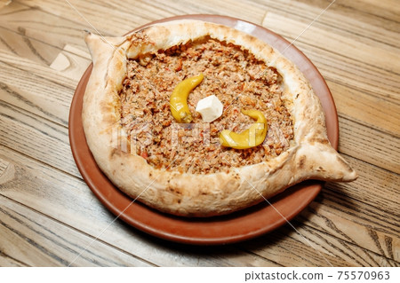 Top view on tasty traditional Adjarian Khachapuri - open baked pie with meat and pepperyolk on wooden tray. Traditional georgian food Top view on tasty traditional Adjarian Khachapuri - open baked pie with meat and pepperyolk on wooden tray. Traditional georgian food 75570963