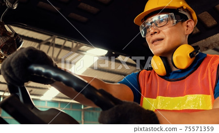 Skillful worker drives forklift in the factory . Skillful worker drives forklift in the factory . 75571359