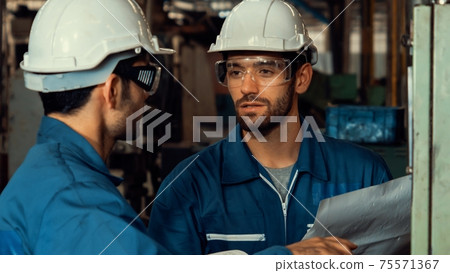 Group of skillful factory workers using machine equipment in workshop 75571367