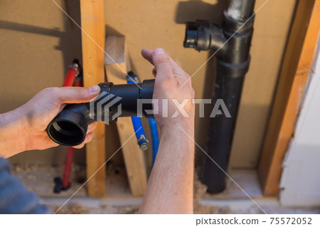 Plumber joining PVC sewage drain pipes on a home under construction Plumber joining PVC sewage drain pipes on a home under construction 75572052