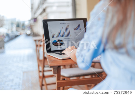 business woman analyzing financial data sitting at a table in a cafe. 75572949