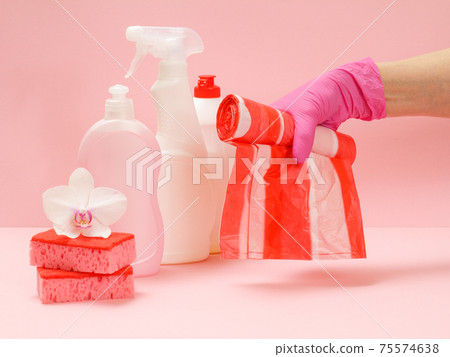 Bottles of dishwashing liquid, sponges and hand with garbage bags on a pink background. Bottles of dishwashing liquid, sponges and hand with garbage bags on a pink background. 75574638