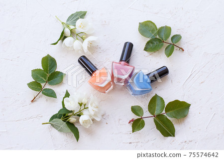 Nail polish bottles with blossoms on white background Nail polish bottles with blossoms on white background 75574642