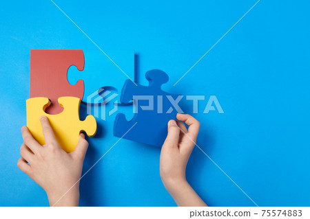 Top view hands of a autistic child arranging color puzzle symbol of awareness for autism spectrum disorder. Autism Awareness Day or month. Top view hands of a autistic child arranging color puzzle symbol of awareness for autism spectrum disorder. Autism Awareness Day or month. 75574883