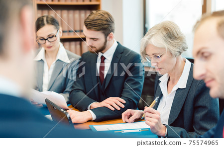 Team of partners in a law firm working diligently on a case Team of partners in a law firm working diligently on a case 75574965